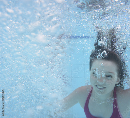 a happy little girl swimming in a pool - underwater photo © Vera Kuttelvaserova