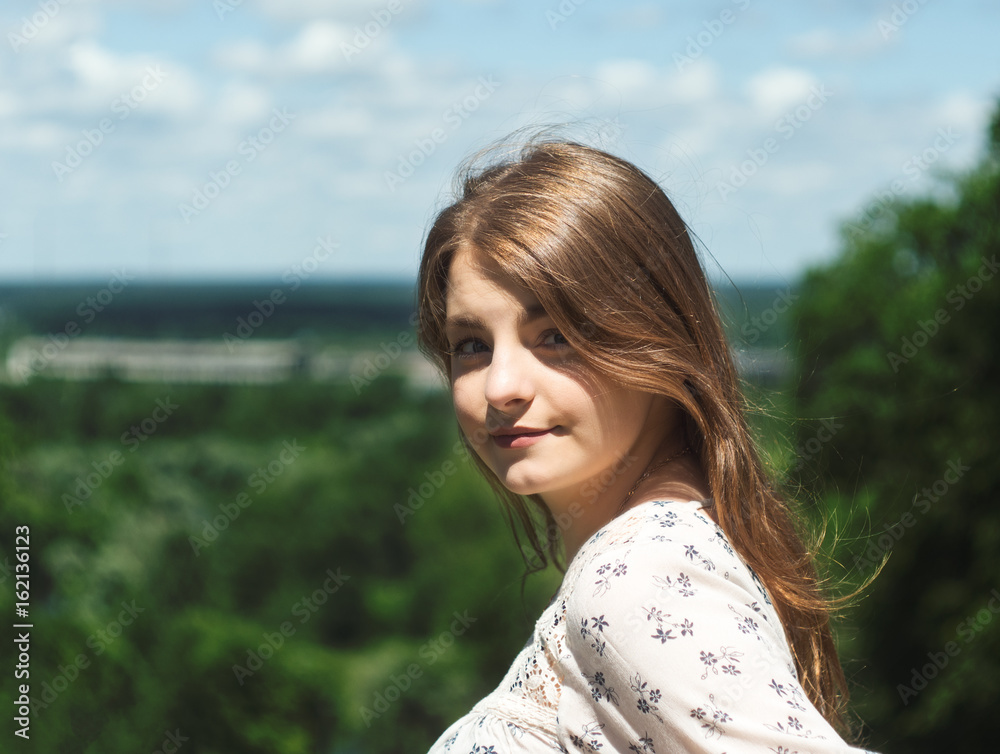 Fototapeta premium girl portrait in three quarters. beautiful girl sitting on a bench in the Park and looking at camera closeup