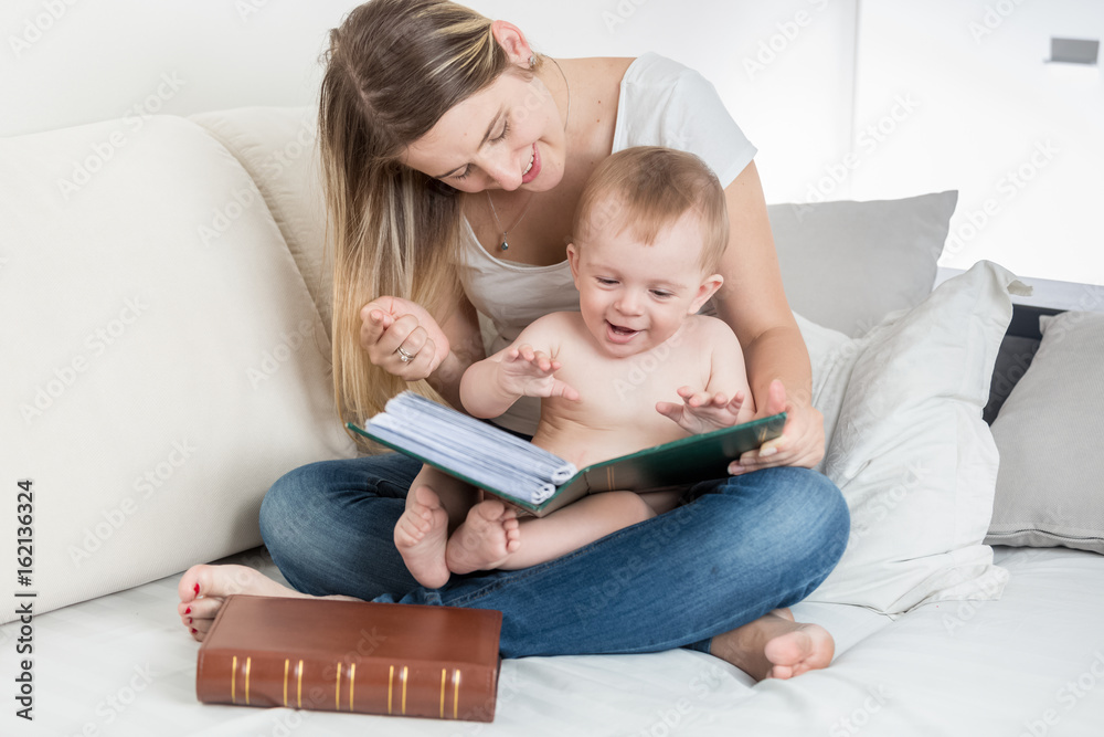 Happy smiling mother looking at photo album with her baby boy Happy smiling mother looking at photo album with her baby boy