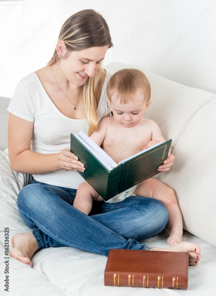 Cute baby boy and mother looking at photos in family album