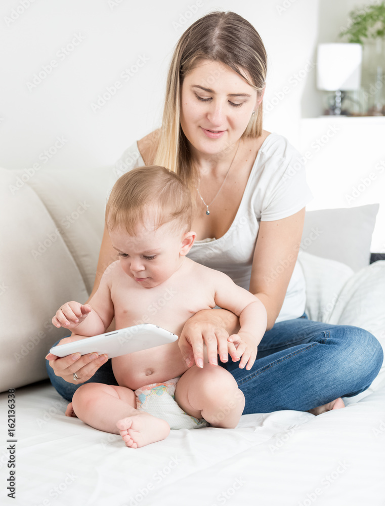Concentrated baby boy and young mother touching screen on tablet PC