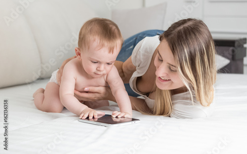 Portrait of smiling mother playing with her baby on tablet computer