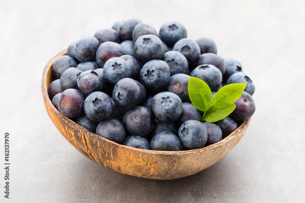 Fresh blueberries natural coconut in a bowl on a gray background.