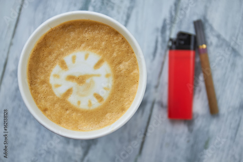 Coffee, lighter and cigarette. Clock latte art close up. Is caffeine addictive.