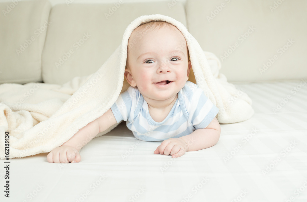 Portrait of surprised baby boy looking at camera from under the blanket Portrait of surprised baby boy looking at camera from under the blanket