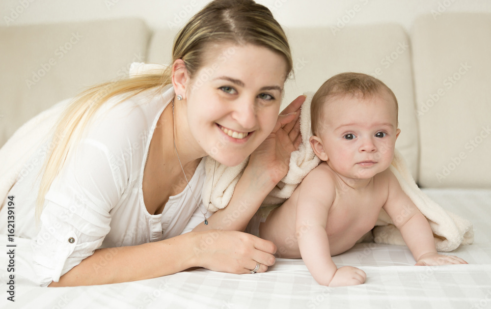 Happy smiling mother and baby covering with blanket on bed Happy smiling mother and baby covering with blanket on bed