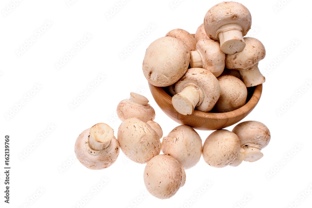 White mushrooms champignons lie in a wooden cup, isolated on a white background White mushrooms champignons lie in a wooden cup, isolated on a white background