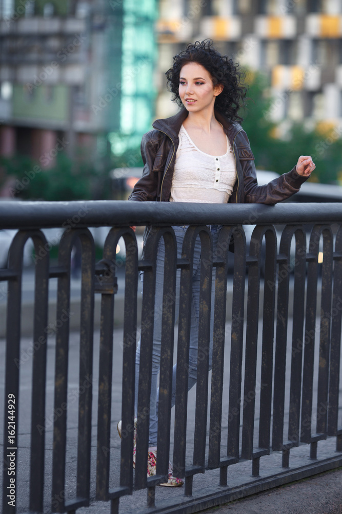 Beautiful young brunette girl on a city bridge.