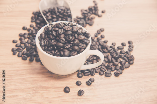 Coffee beans and cup on wooden background, warm tone