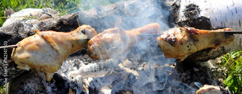 Chicken legs on a skewer over a fire.