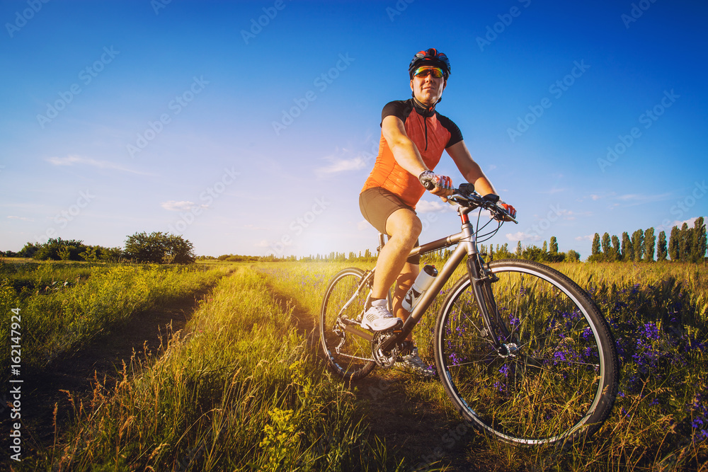 A man cyclist is riding on a blooming poppy meadow