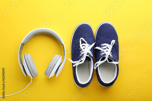 Blue sport shoes with headphones on yellow background