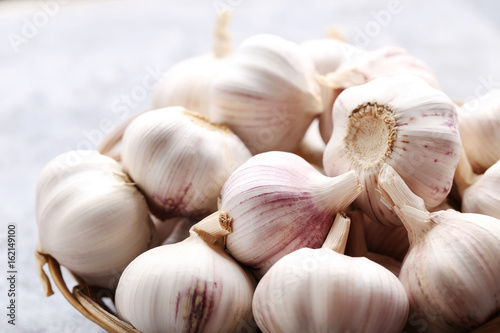 Garlic in basket on grey wooden table photo