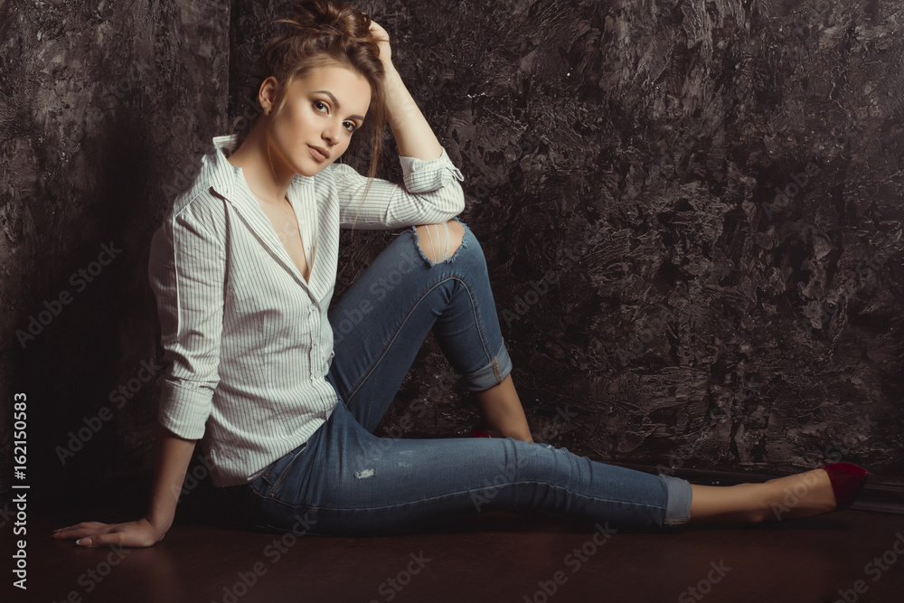 Pretty brunette woman with natural makeup in shirt and torn jeans