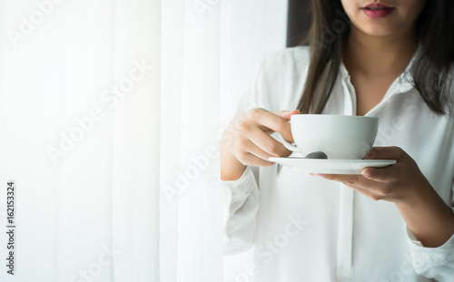 Asian Woman holding a mug of coffee in the morning on the weekend in Relax and weekend concept.
