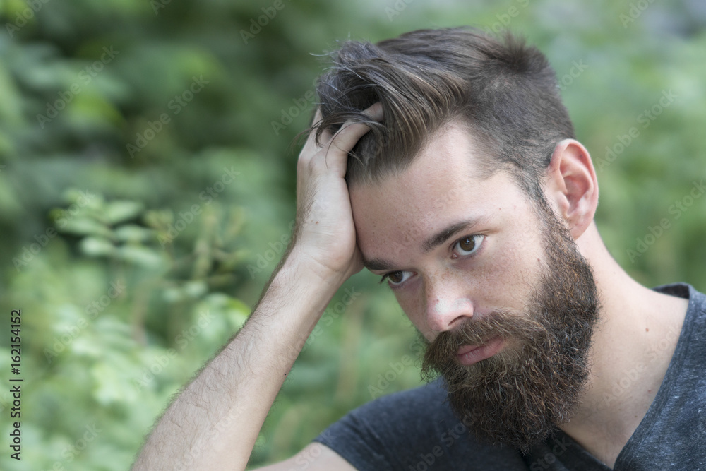 Close up portrait of a thoughtful bearded guy resting in park Close up portrait of a thoughtful bearded guy resting in park