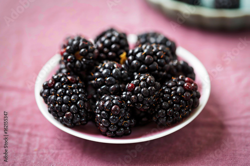 Blackberries on pink plate and violet background