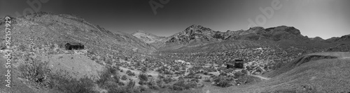 Panorama black and white shot of mountains and desert ghost town