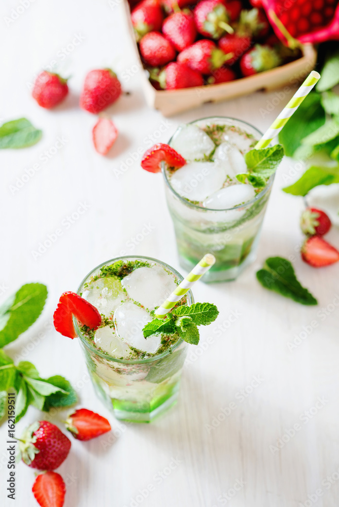 Alcoholic and non-alcoholic refreshing drinks, cold sparkling cocktail with ice, green mint and fresh strawberries in a beautiful glass on a light background Alcoholic and non-alcoholic refreshing drinks, cold sparkling cocktail with ice, green mint and fresh strawberries in a beautiful glass on a light background