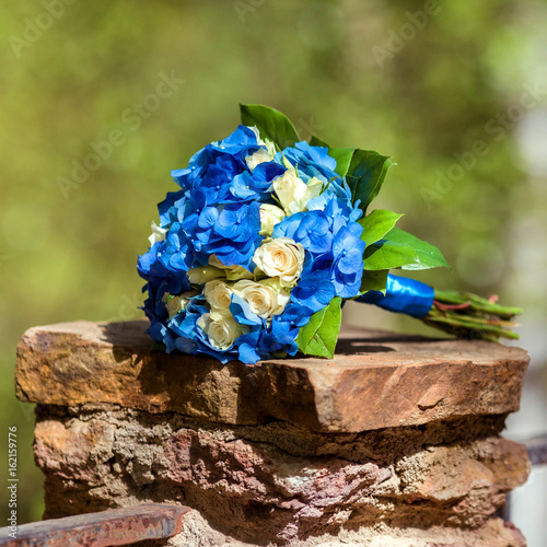 A wedding bouquet with blue flowers on the stone photo