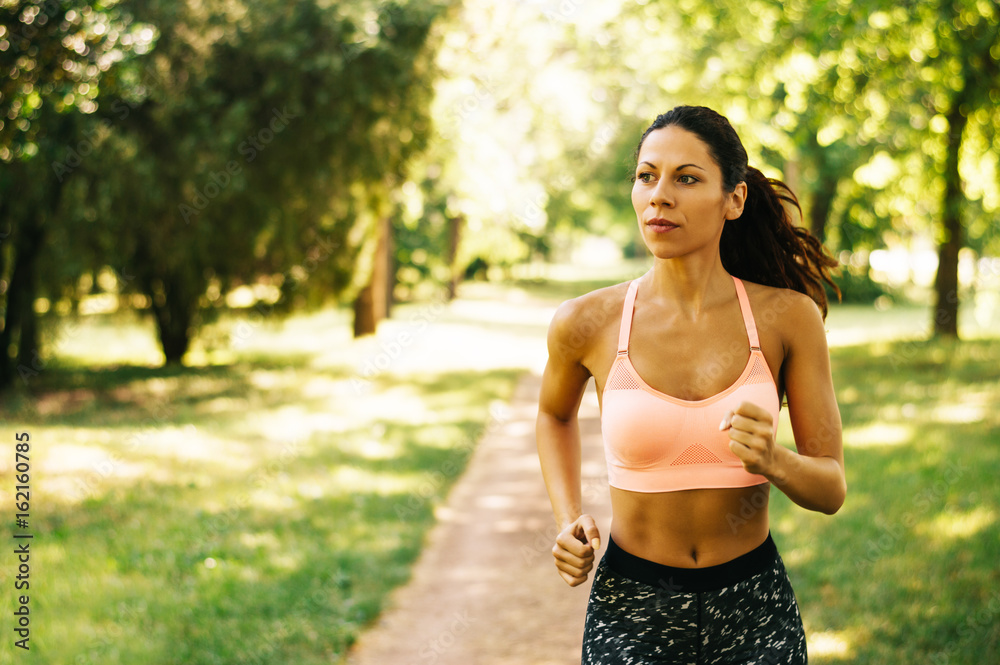 Female runner jogging during outdoor workout in a park Female runner jogging during outdoor workout in a park