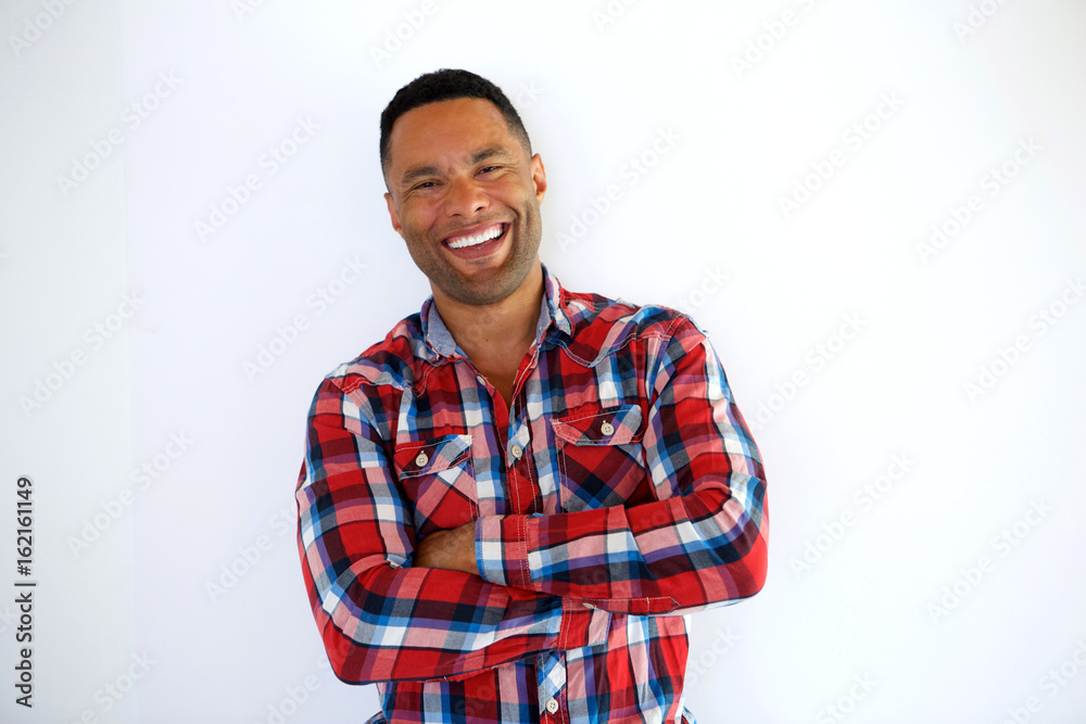 Smiling black young man with arms crossed standing against white background Smiling black young man with arms crossed standing against white background