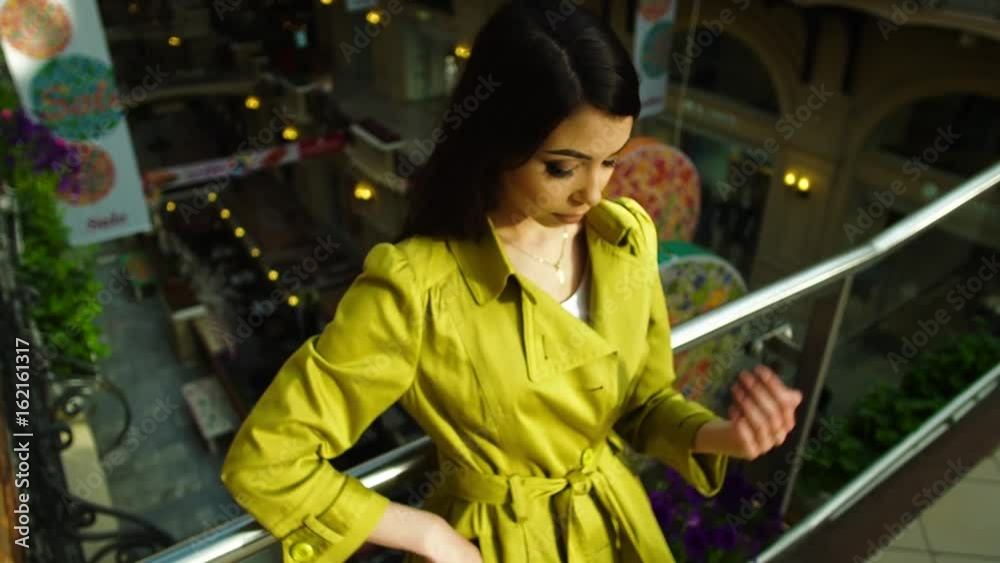 Business woman using smartphone in the mall, shopping center. Girl in thought looking out in the distance Business woman using smartphone in the mall, shopping center. Girl in thought looking out in the distance
