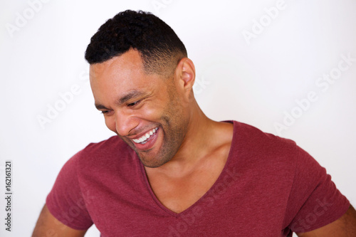 happy african american man looking down and smiling against white background