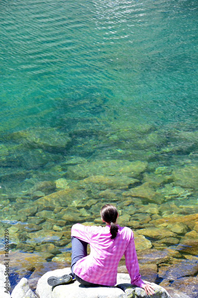 Woman sitting near the lake in mountains