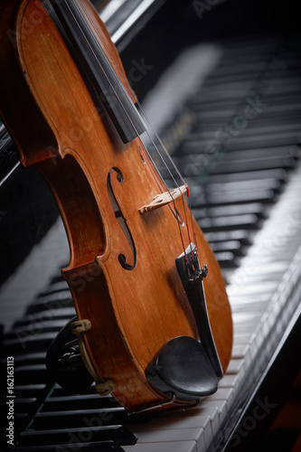 деревянная скрипка на черном рояле