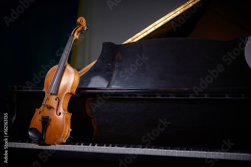 деревянная скрипка на черном рояле