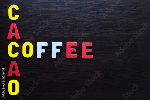 Coffee and cacao colorful letters on dark brown wood.