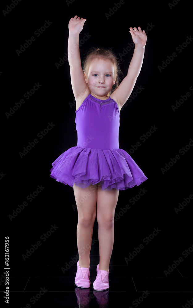 Little ballerina girl in a purple tutu dancing in a dark room Little ballerina girl in a purple tutu dancing in a dark room