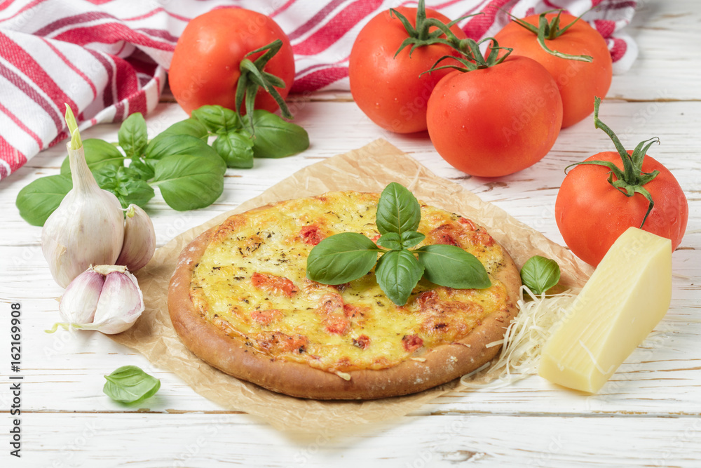 Baked flat bread with tomatoes, cheese, garlic and Basil on a white wooden table. Rustic style. Selective focus