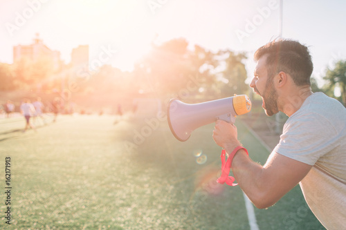 The head coach screams into the megaphone. Football game. Concept