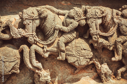 Horse rider on stone sculptures of decoration inside the Hindu temple. Walls with artworks and designed patterns of 12th centur Hoysaleshwara temple in Halebidu, India. photo