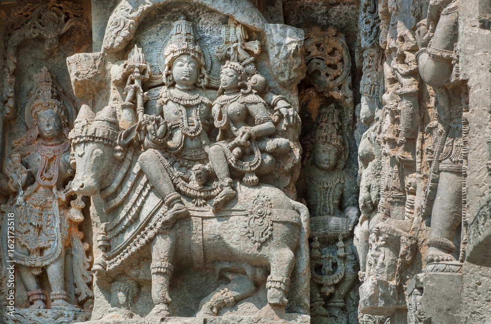 Shiva, Parvati and bull Nandi on wall of Indian temple. Example of ancient architecture, 12th century decoration inside the Hindu temple Hoysaleshwara in Halebidu, India.