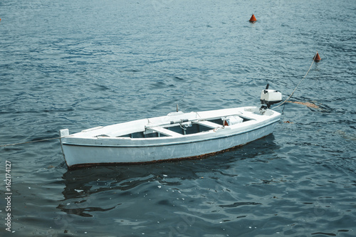 Single boat floating on the water surface in Montenegro background. © Paweł Michałowski