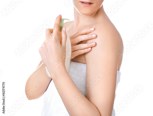 Young woman after shower applying cosmetics onto skin, on white background