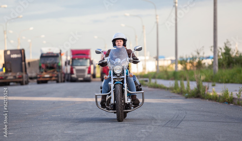European female motorcyclist driving on chopper motorbike on asphalt highway  front view