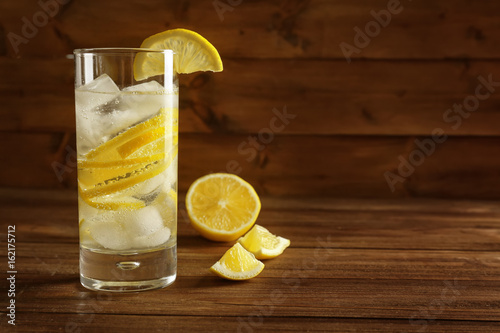 Glass of cold lemon water on wooden table