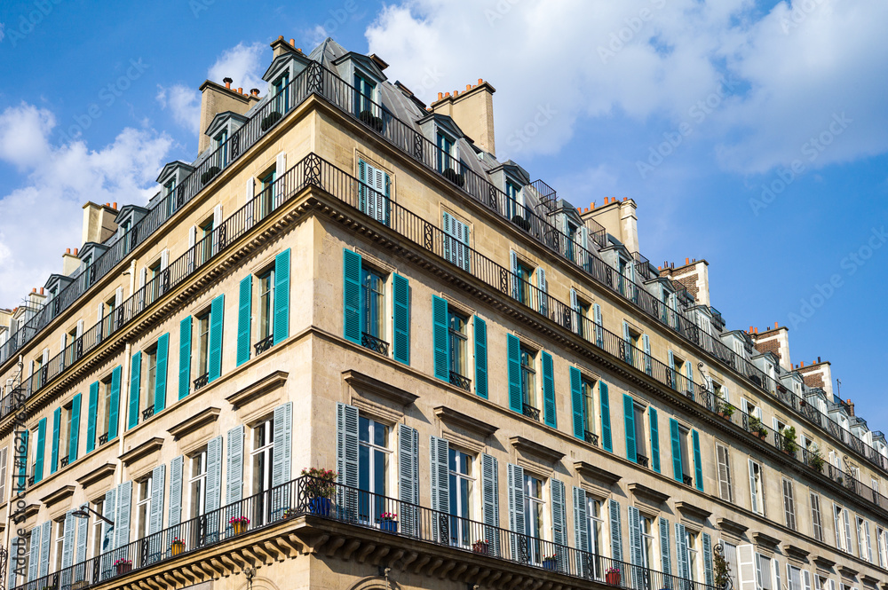 A typical Haussmannian building in Paris with balconies and shutters under a warm light of late afternoon.