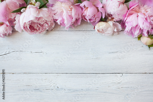 Pink flowers peonies on a white wooden background, space for text greeting