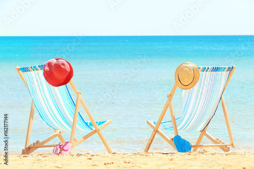 Pair of beach chairs and accessories at sea shore. Vacation concept