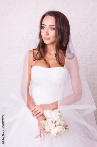 Wedding dress. Beautiful curly bride with tan body in white wedding dress pose in studio