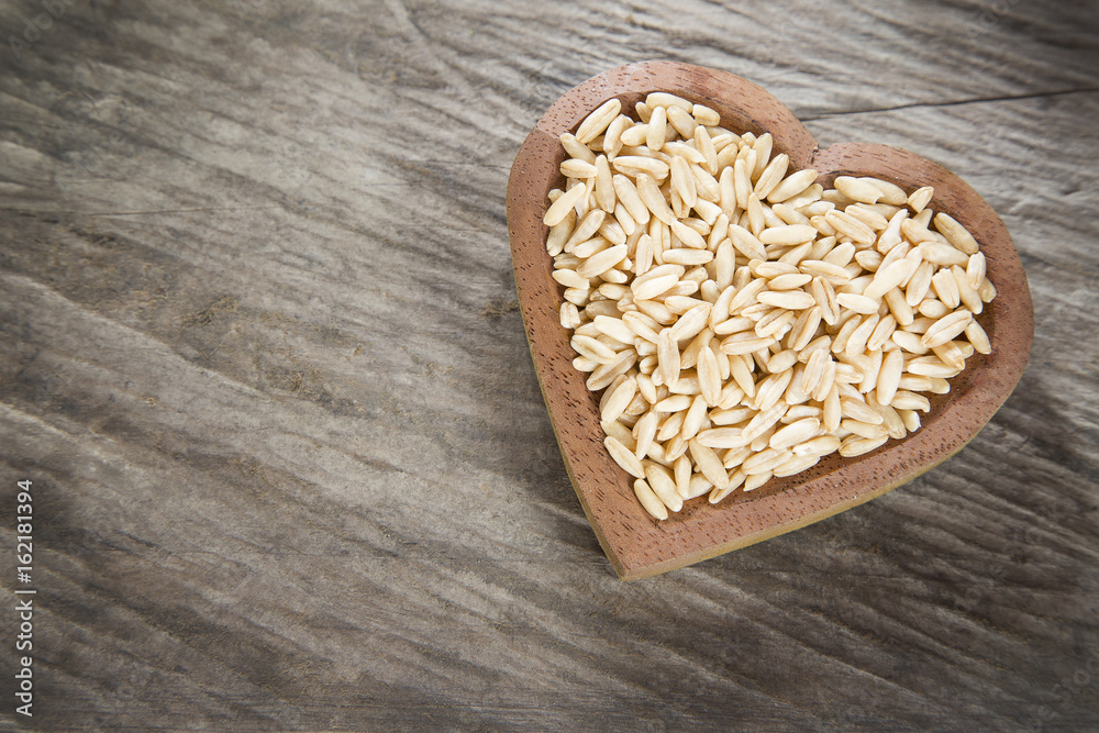 Oat grains on wooden background - Avena sativa