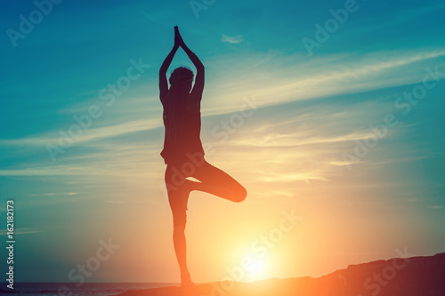Meditation woman on the ocean during amazing sunset. Yoga silhouette. Fitness and healthy lifestyle.