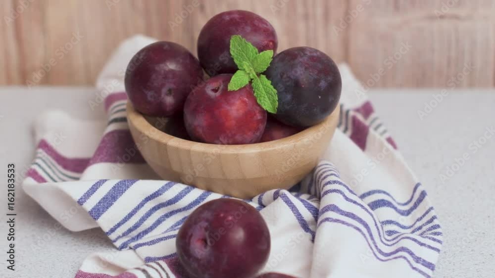 Delicious red plums in a wooden bowl on kitchen countertop. Delicious red plums in a wooden bowl on kitchen countertop.