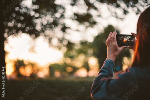 Girl taking photo of sunset