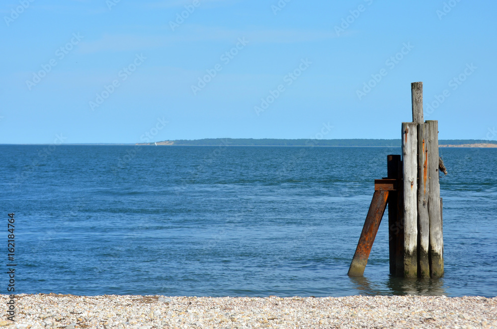 Wooden dock piling on rocky beach 